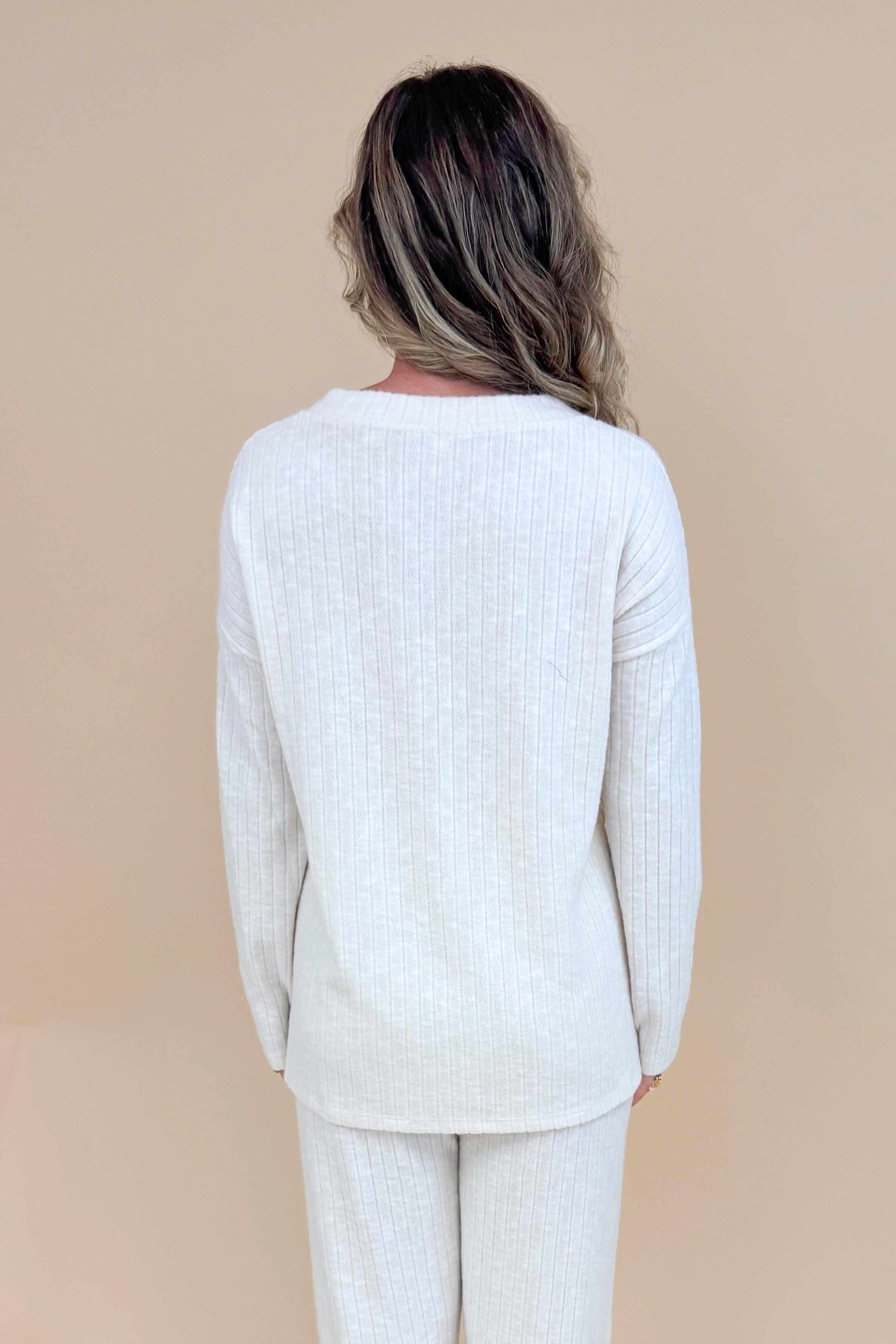 Back view of model wearing cream ribbed lounge long sleeve top.