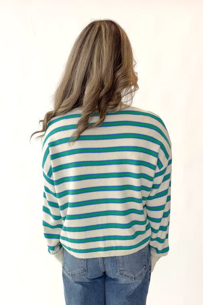 Back view of woman wearing Blue and Green Striped Sweater with jeans against white studio background.