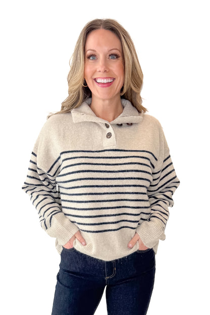 Front view of woman wearing Oatmeal and Navy Striped Button Detail Sweater with jeans against white studio background.