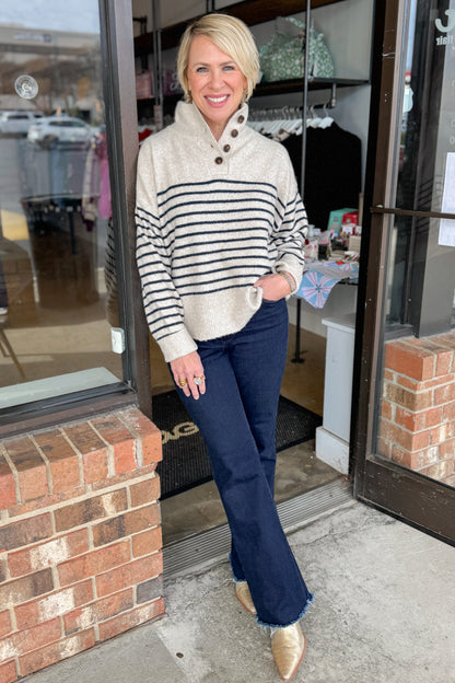 Front view of woman wearing Oatmeal and Navy Striped Button Detail Sweater with jeans at a boutique.