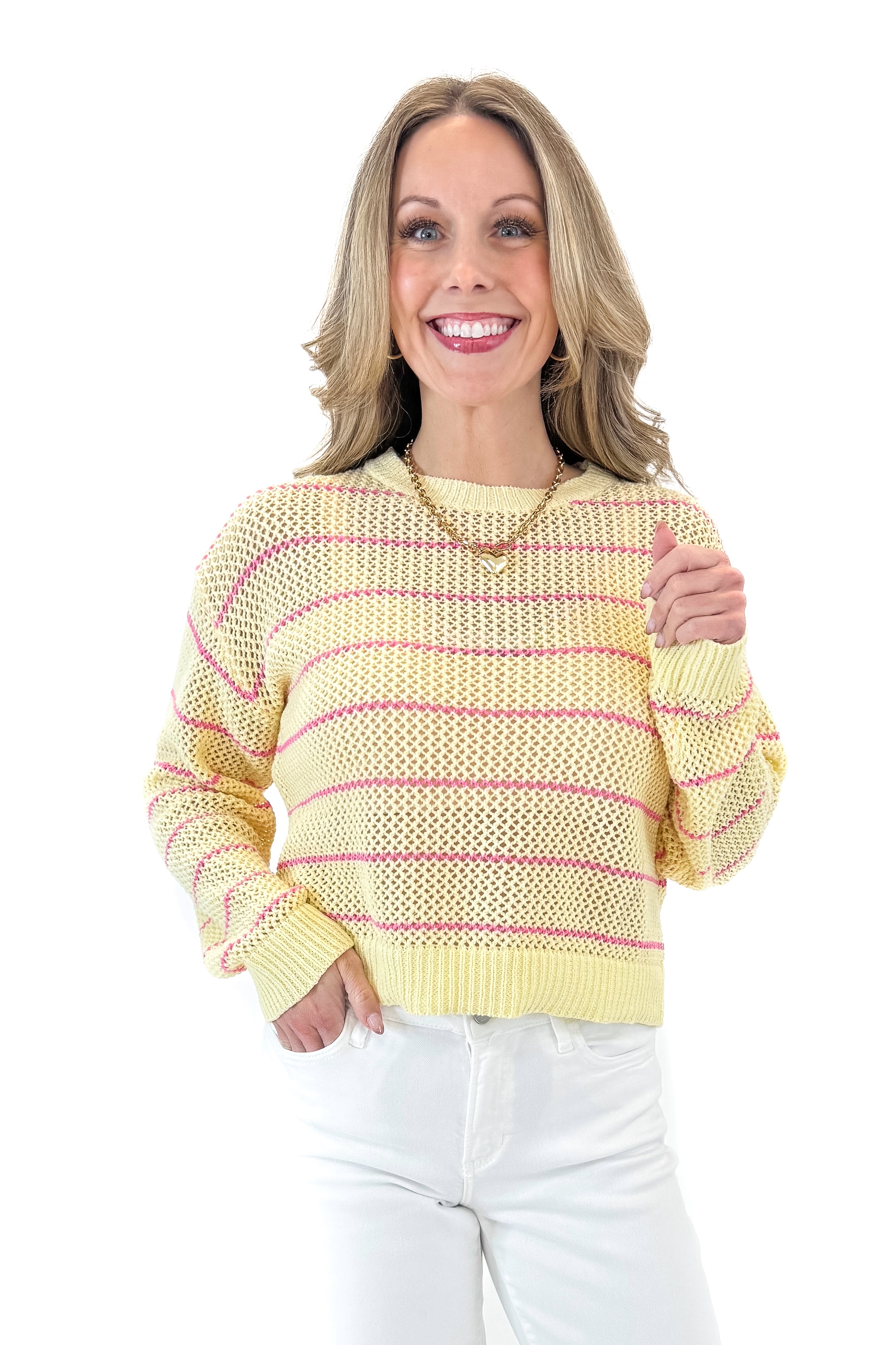 Front view of woman wearing Yellow &amp; Pink Striped Loose Knit Sweater with jeans against white studio background.