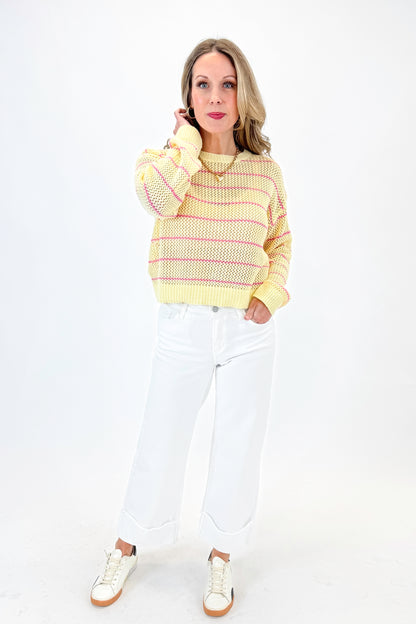 Front view of woman wearing Yellow &amp; Pink Striped Loose Knit Sweater with jeans against white studio background.