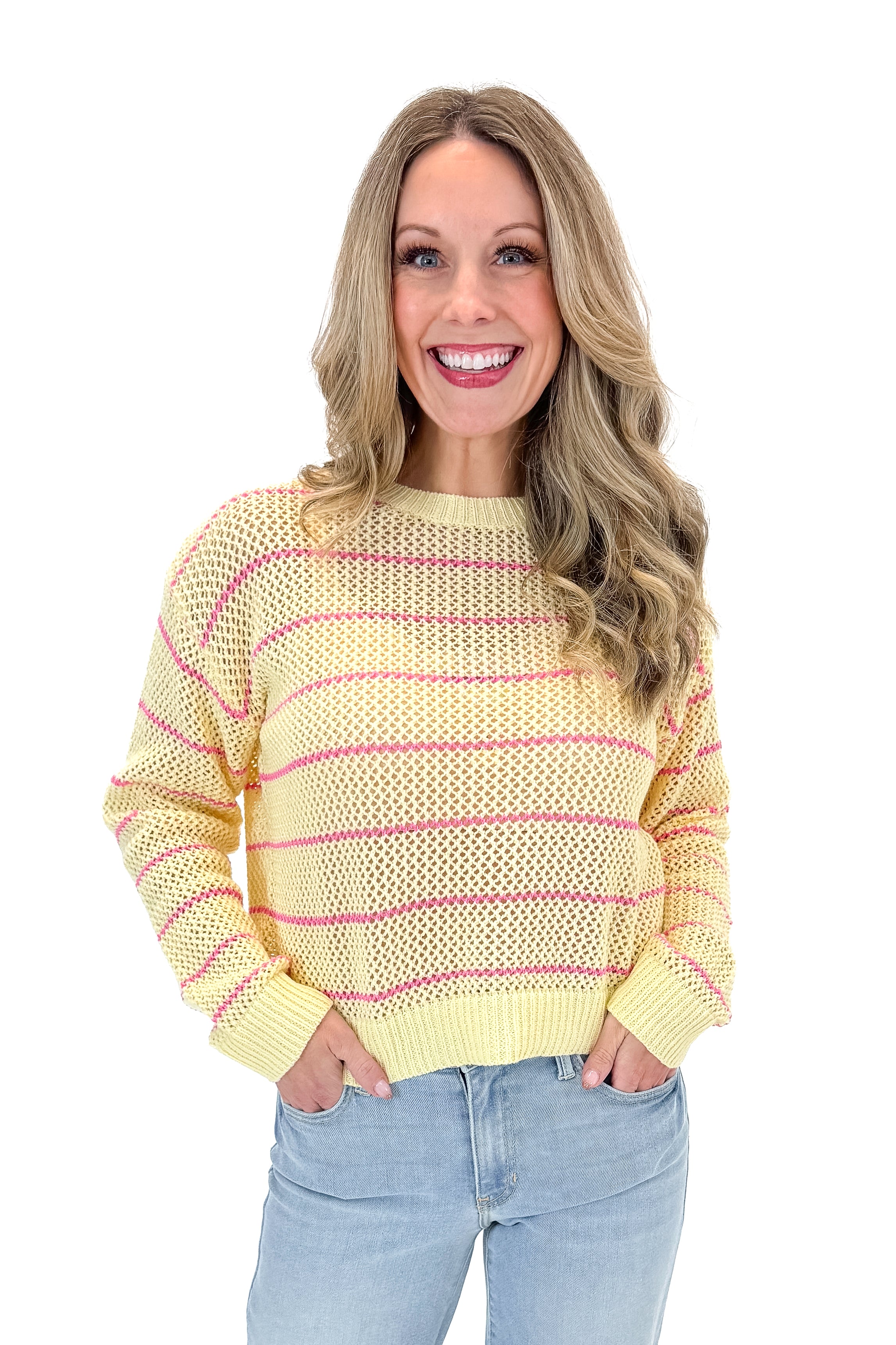 Front view of woman wearing Yellow &amp; Pink Striped Loose Knit Sweater with jeans against white studio background.