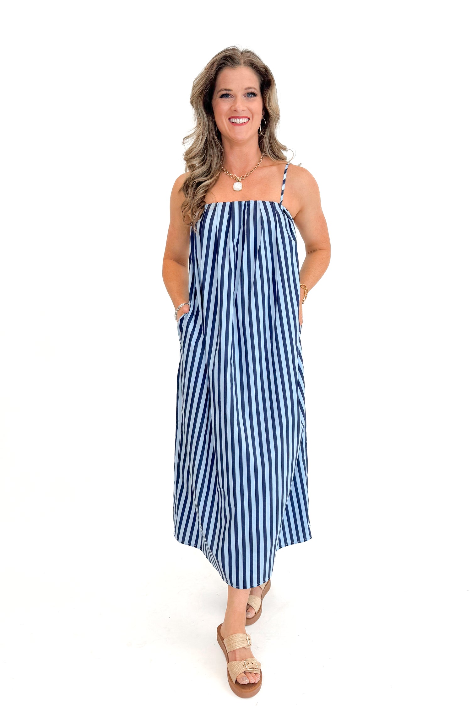 Front view of woman wearing Blue &amp; Navy Striped Midi Dress with sandals against white studio background.