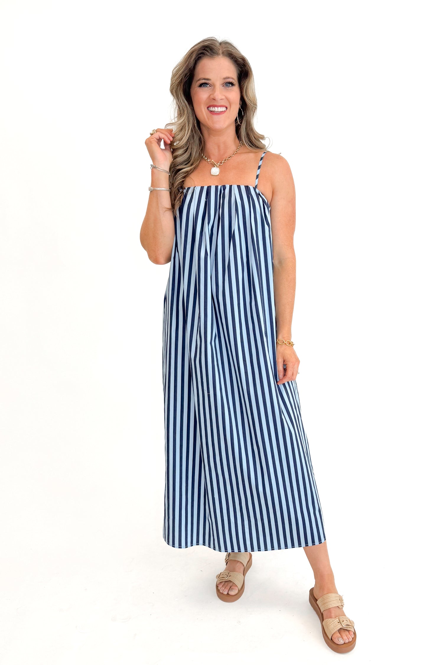 Front view of woman wearing Blue &amp; Navy Striped Midi Dress with sandals against white studio background.