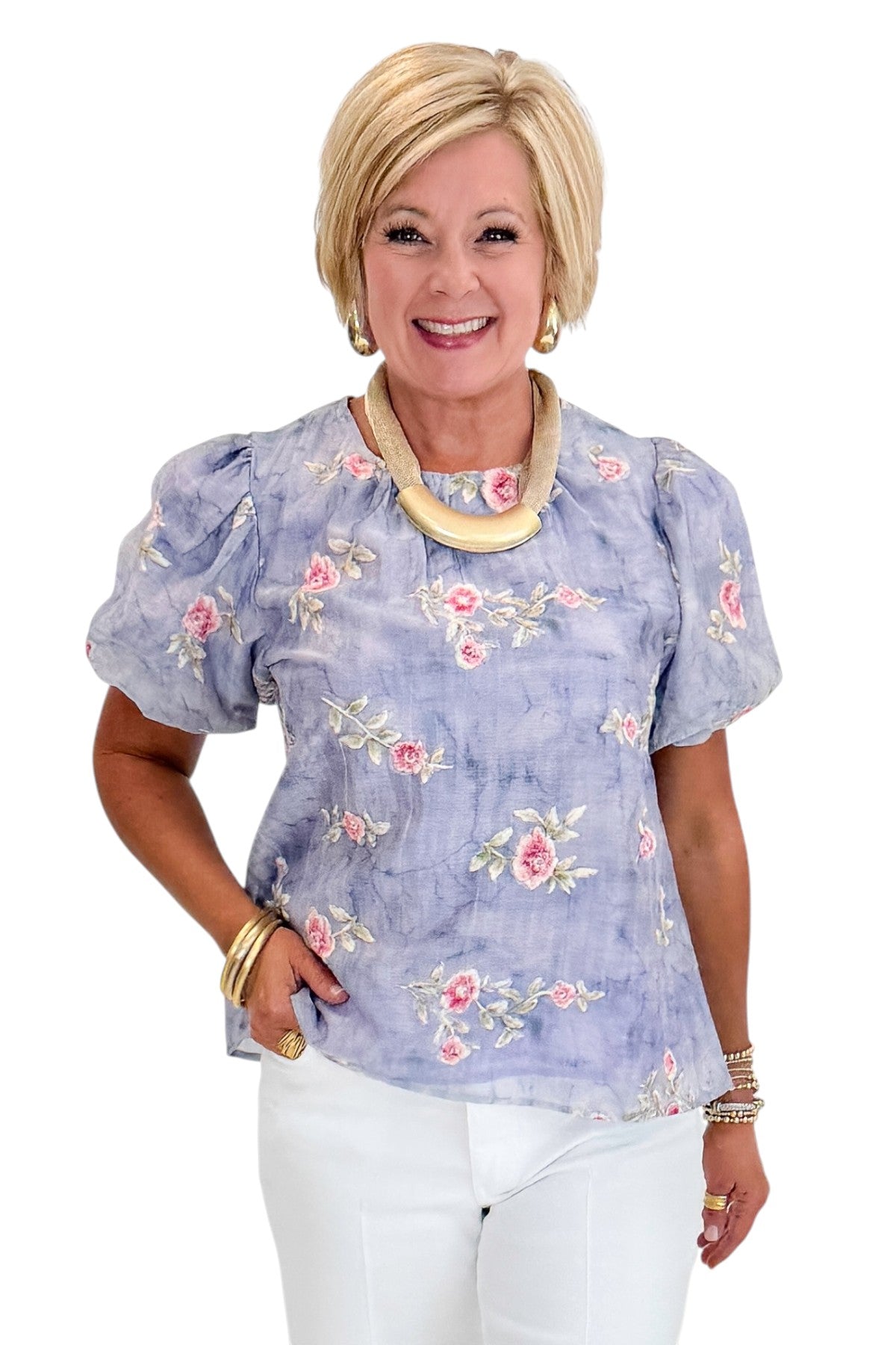 Front view of woman wearing Swagger Boutique’s Washed Blue Floral Puff Sleeve Top with jeans against white studio background.