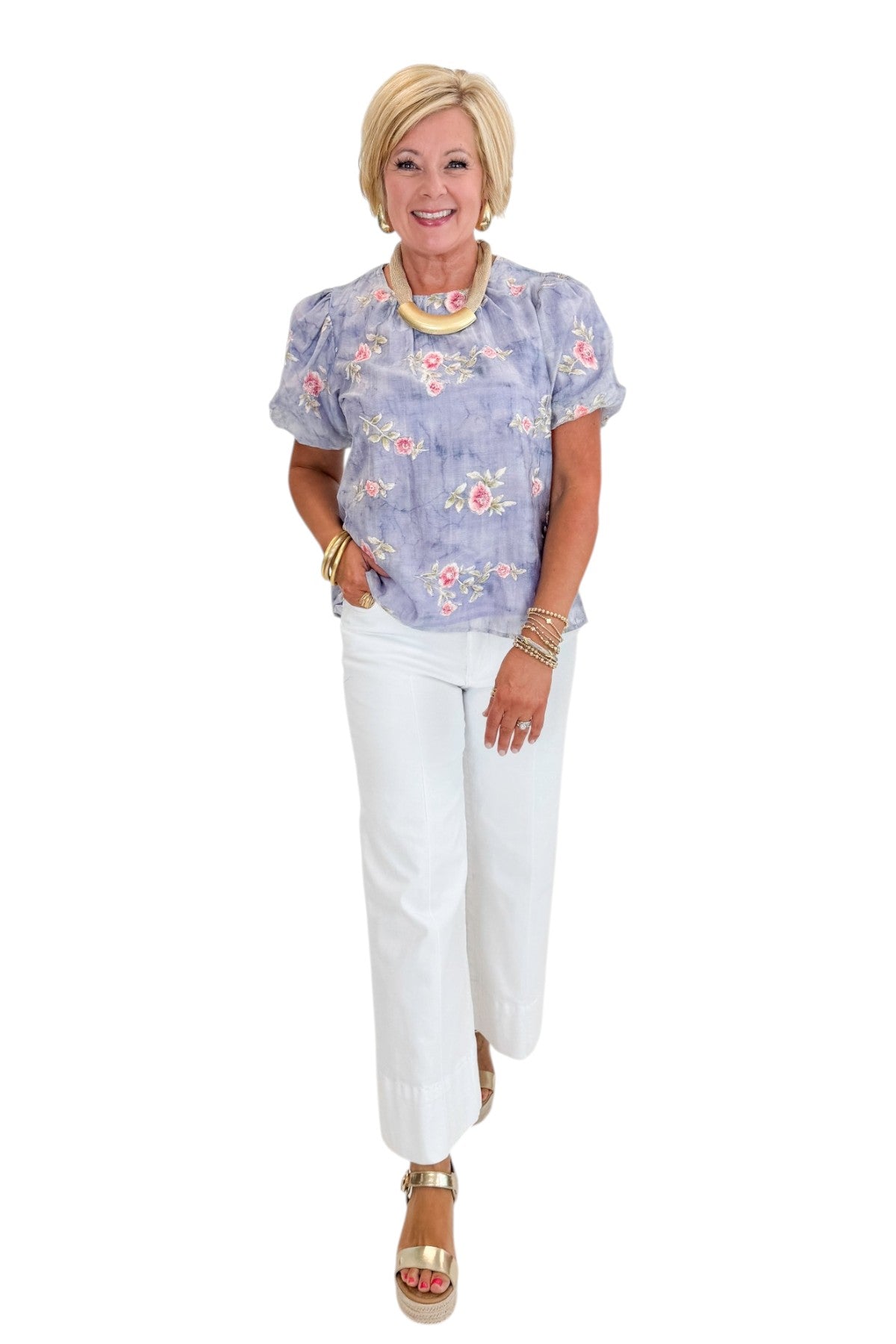 Front view of woman wearing Swagger Boutique’s Washed Blue Floral Puff Sleeve Top with jeans against white studio background.