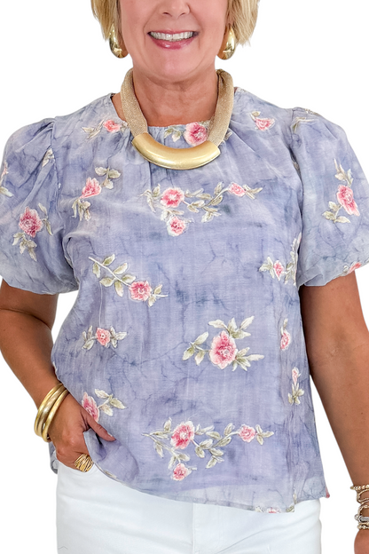 Front detail view of woman wearing Swagger Boutique’s Washed Blue Floral Puff Sleeve Top with jeans against white studio background.