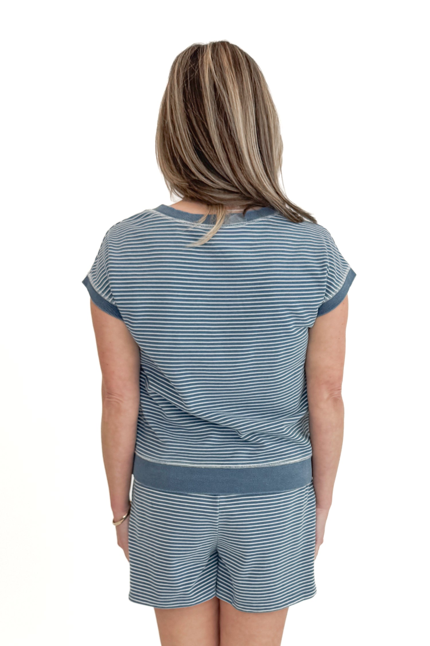 Back view of woman wearing Washed Blue Striped Drawstring Shorts with matching top against white studio background.