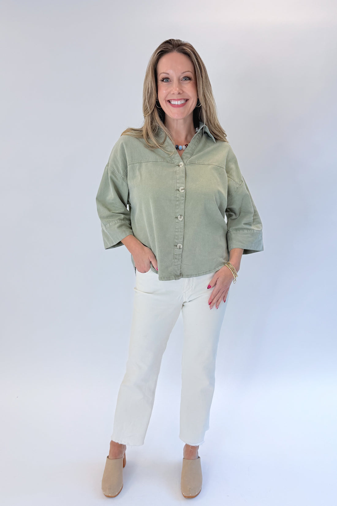 Front view of woman wearing Swagger Boutique’s Washed Olive 3/4 Sleeve Button Down Top with jeans against white studio background.