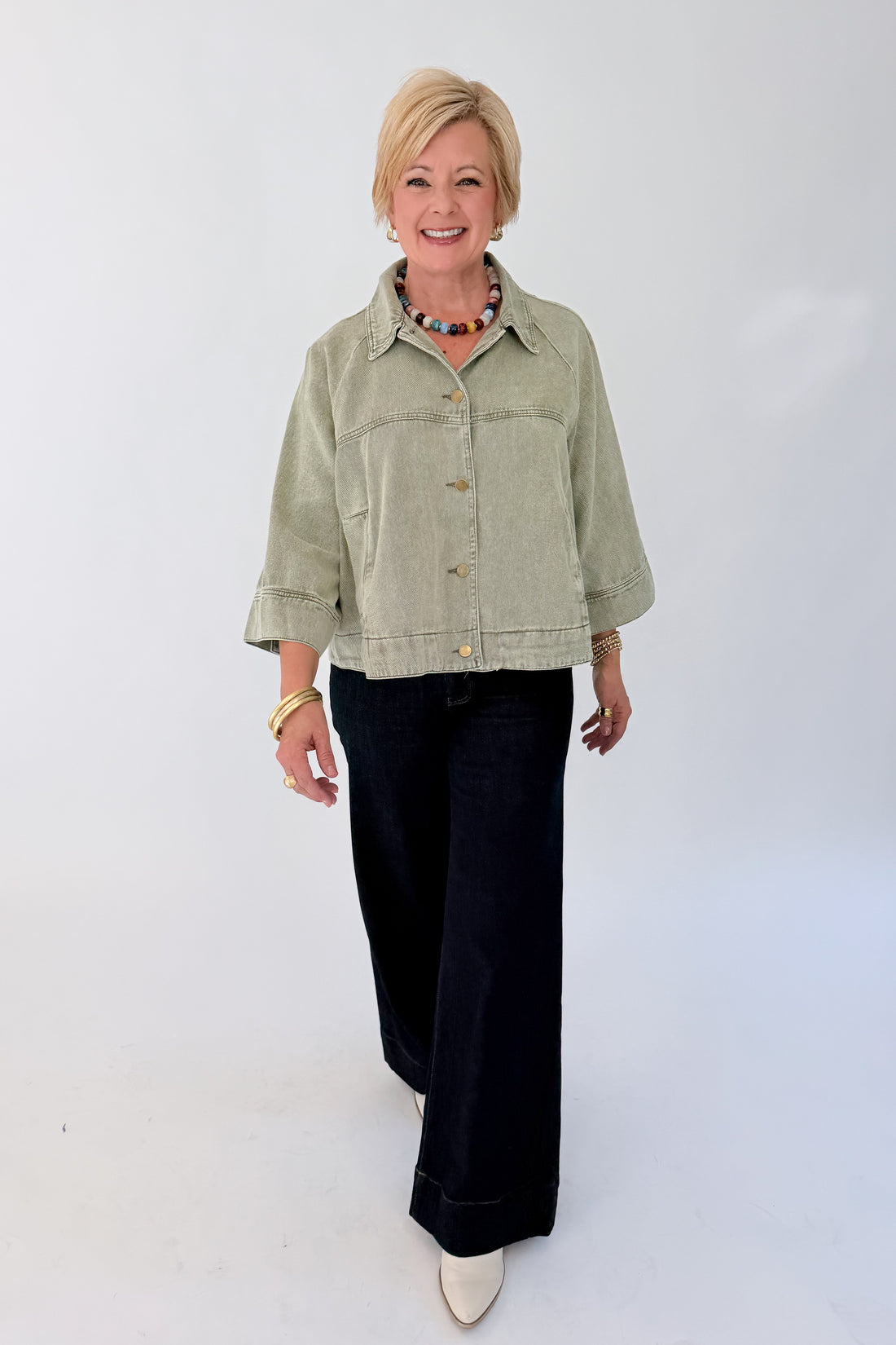 Front view of woman wearing Swagger Boutique’s Washed Olive Utility Jacket with jeans against white studio background.