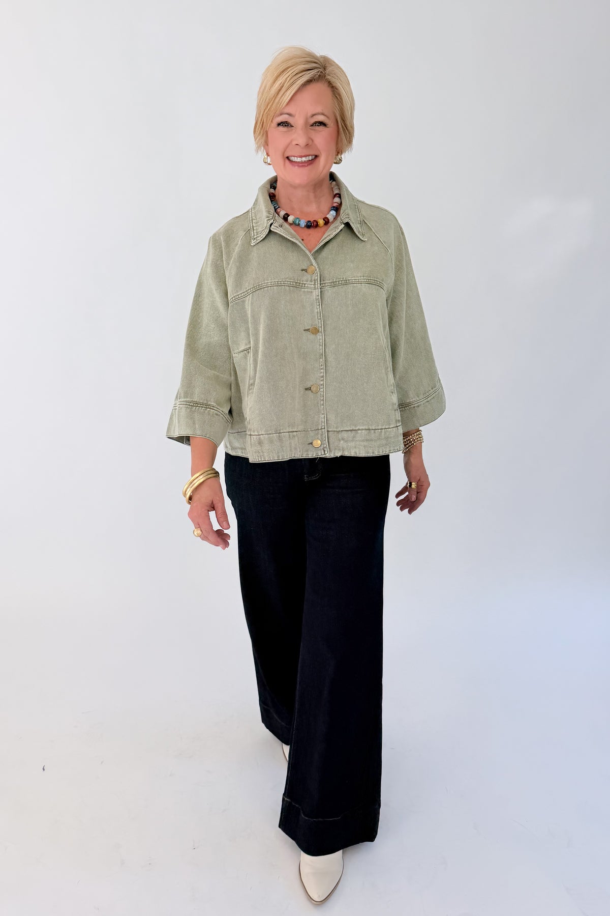 Front view of woman wearing Swagger Boutique’s Washed Olive Utility Jacket with jeans against white studio background.