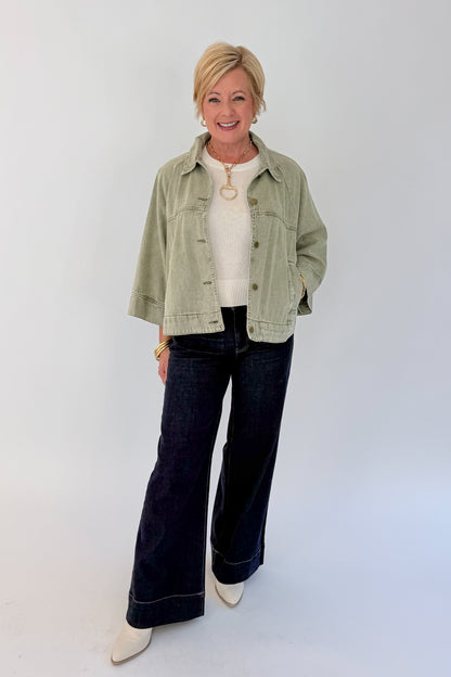 Front view of woman wearing Swagger Boutique’s Washed Olive Utility Jacket with jeans against white studio background.