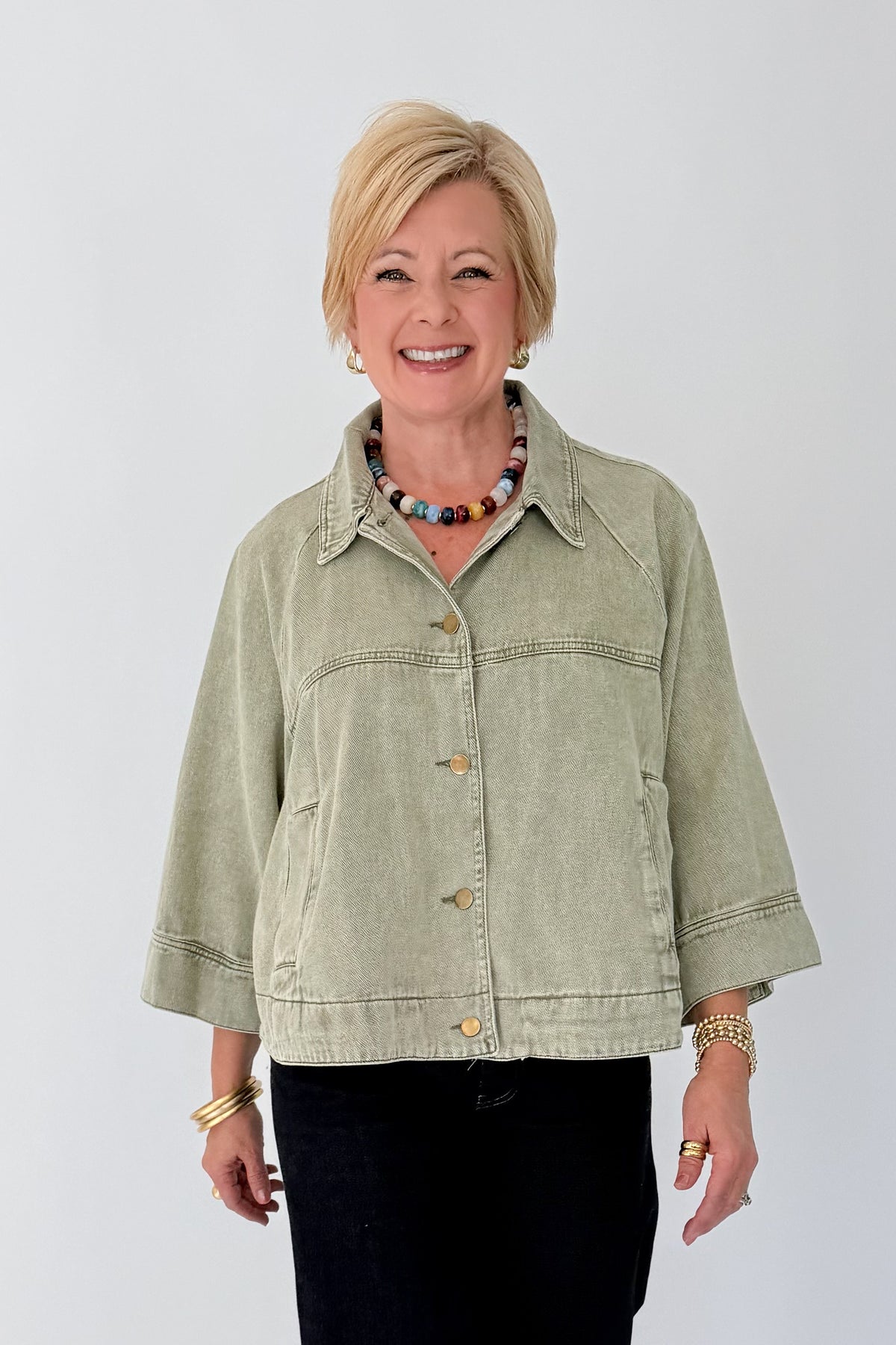 Front view of woman wearing Swagger Boutique’s Washed Olive Utility Jacket with jeans against white studio background.