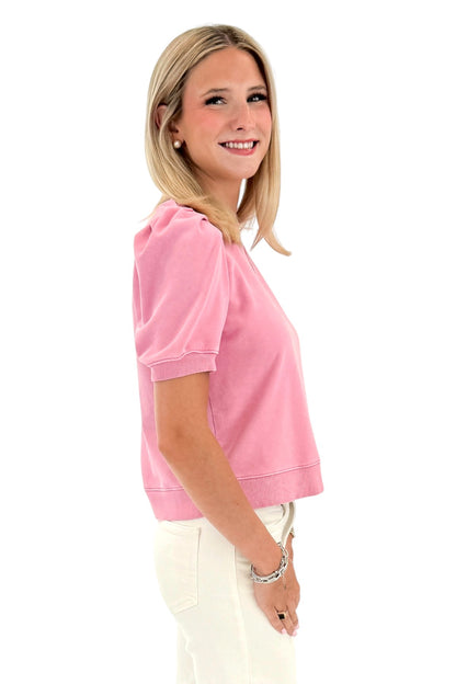 Side view of woman wearing Swagger Boutique’s Washed Pink Short Sleeve Sweatshirt with jeans against white studio background.