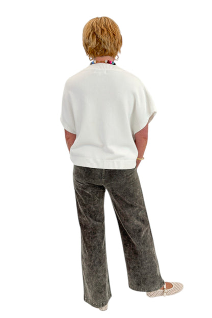 Back view of woman wearing Swagger Boutique’s Ivory Light Weight Short Sleeve Sweater with Washed Stone Corduroy Pants against white studio background.