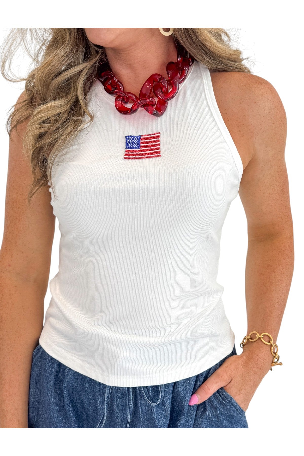 Front view of woman wearing Swagger Boutique’s White Beaded Flag Tank with jean shorts against white studio background.