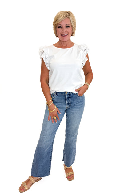 Front view of woman wearing Swagger Boutique’s White Cap Sleeve Eyelet Top with jeans against white studio background.
