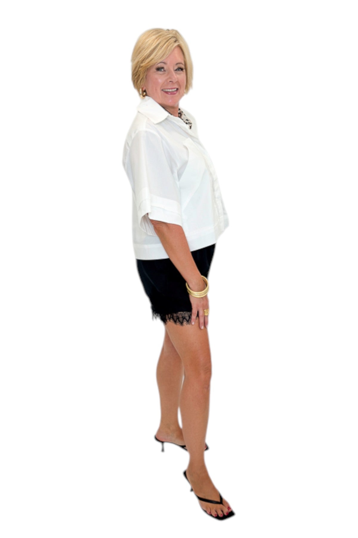 Side view of woman wearing Swagger Boutique’s White Collared Short Sleeve Top with Black Lace Hem Shorts by Entro against white studio background.