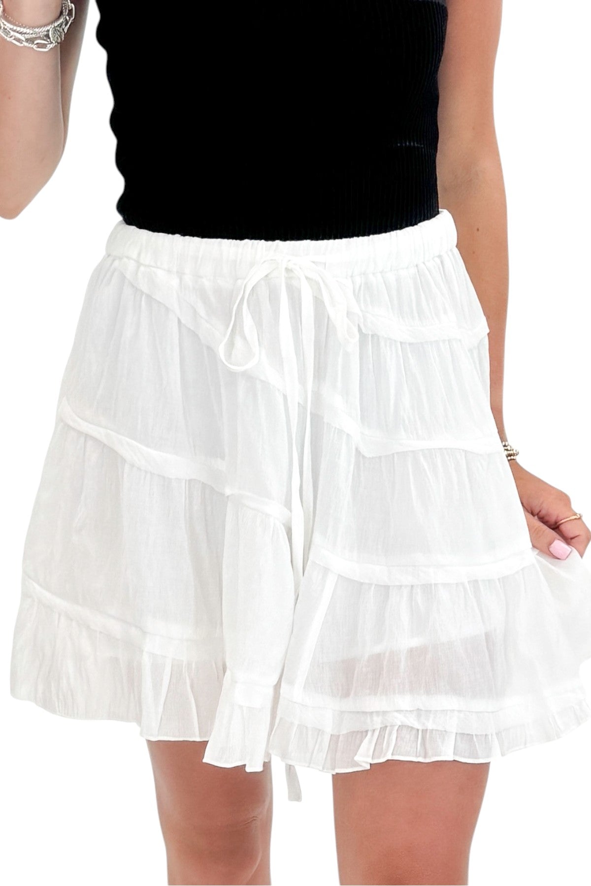 Front detail view of woman wearing Swagger Boutique’s White Diagonal Seam Mini Skirt with black top against white studio background.