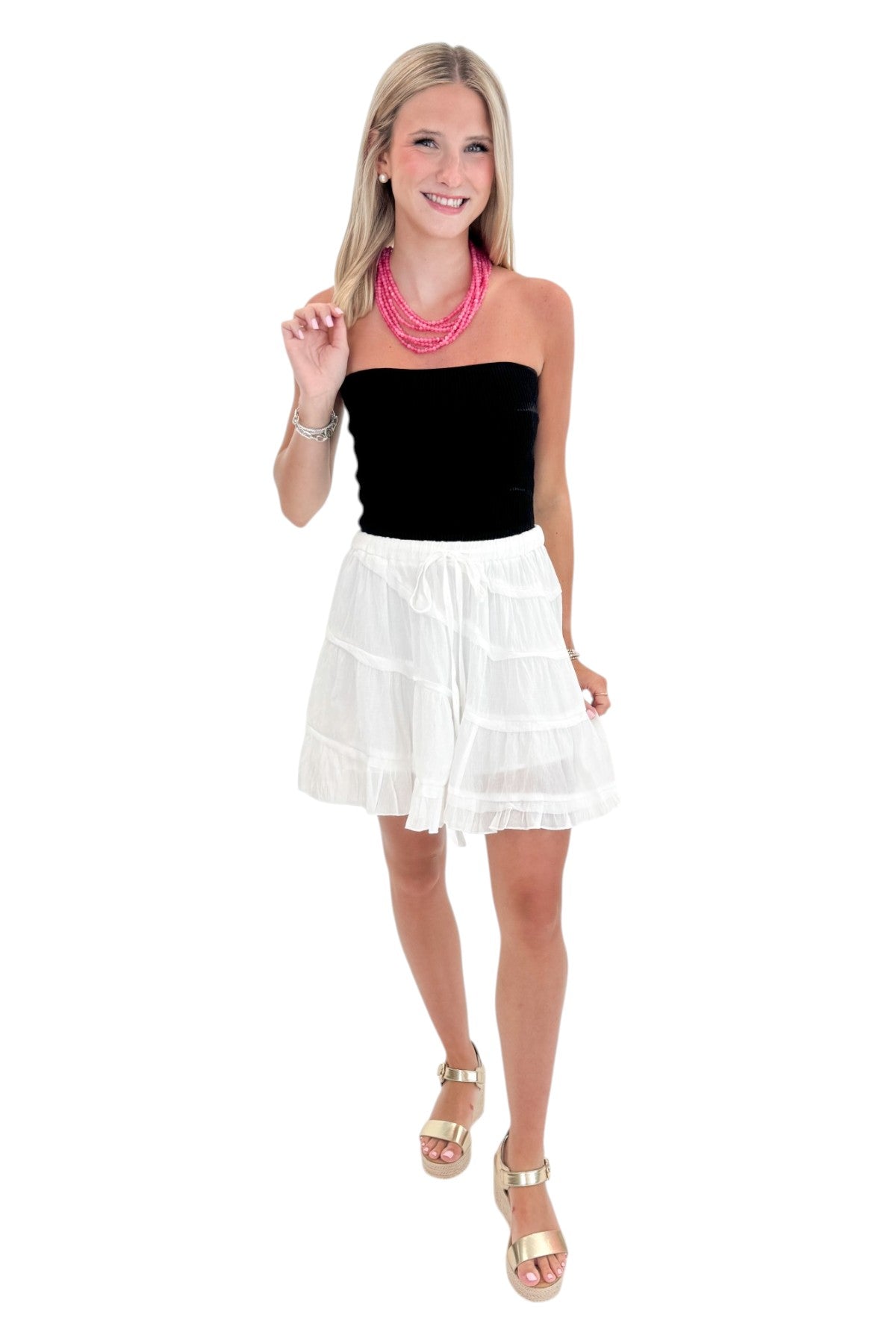 Front view of woman wearing Swagger Boutique’s White Diagonal Seam Mini Skirt with black top against white studio background.