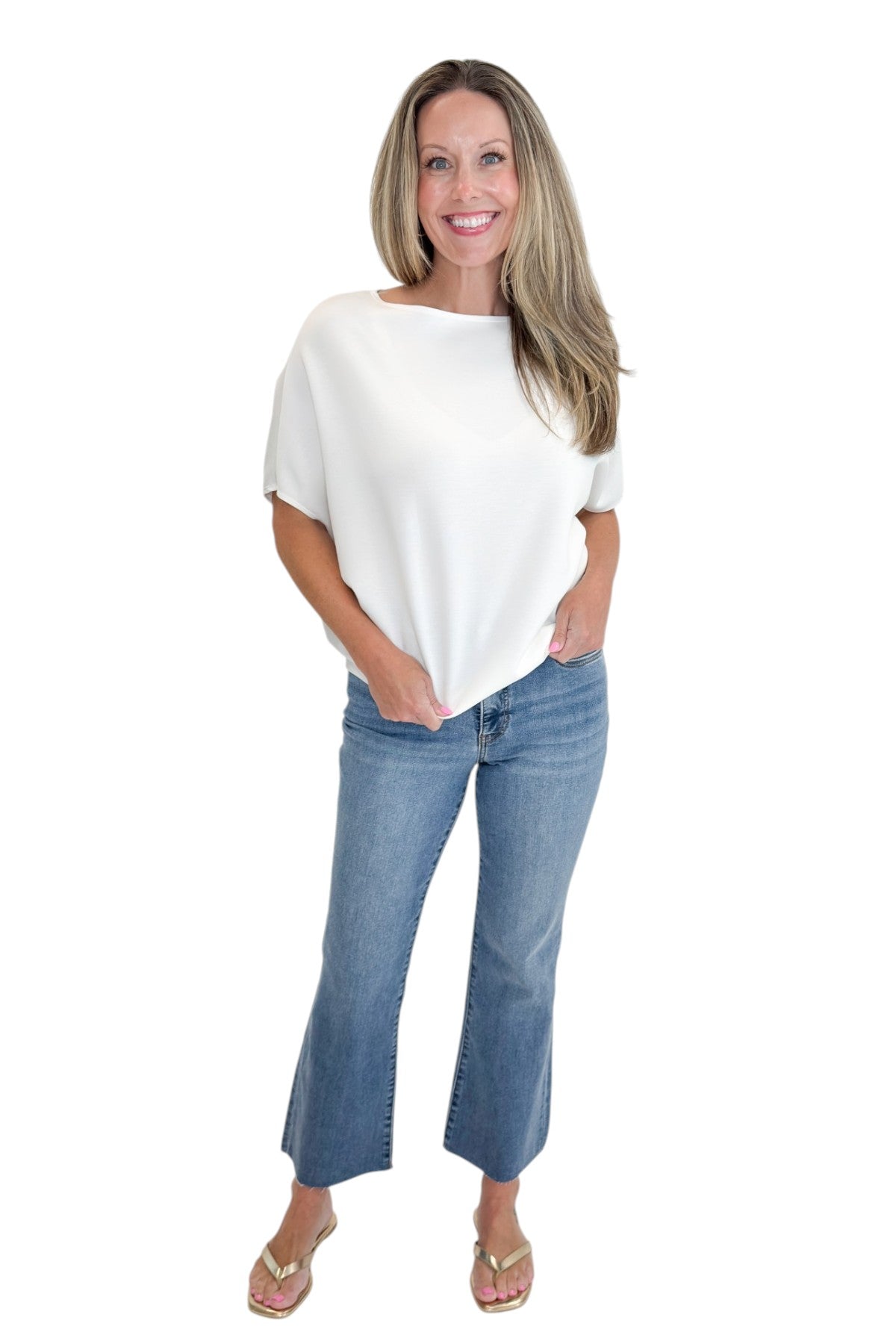 Front view of woman wearing Swagger Boutique’s Off White Dolman Sleeve Top with jeans against white studio background.