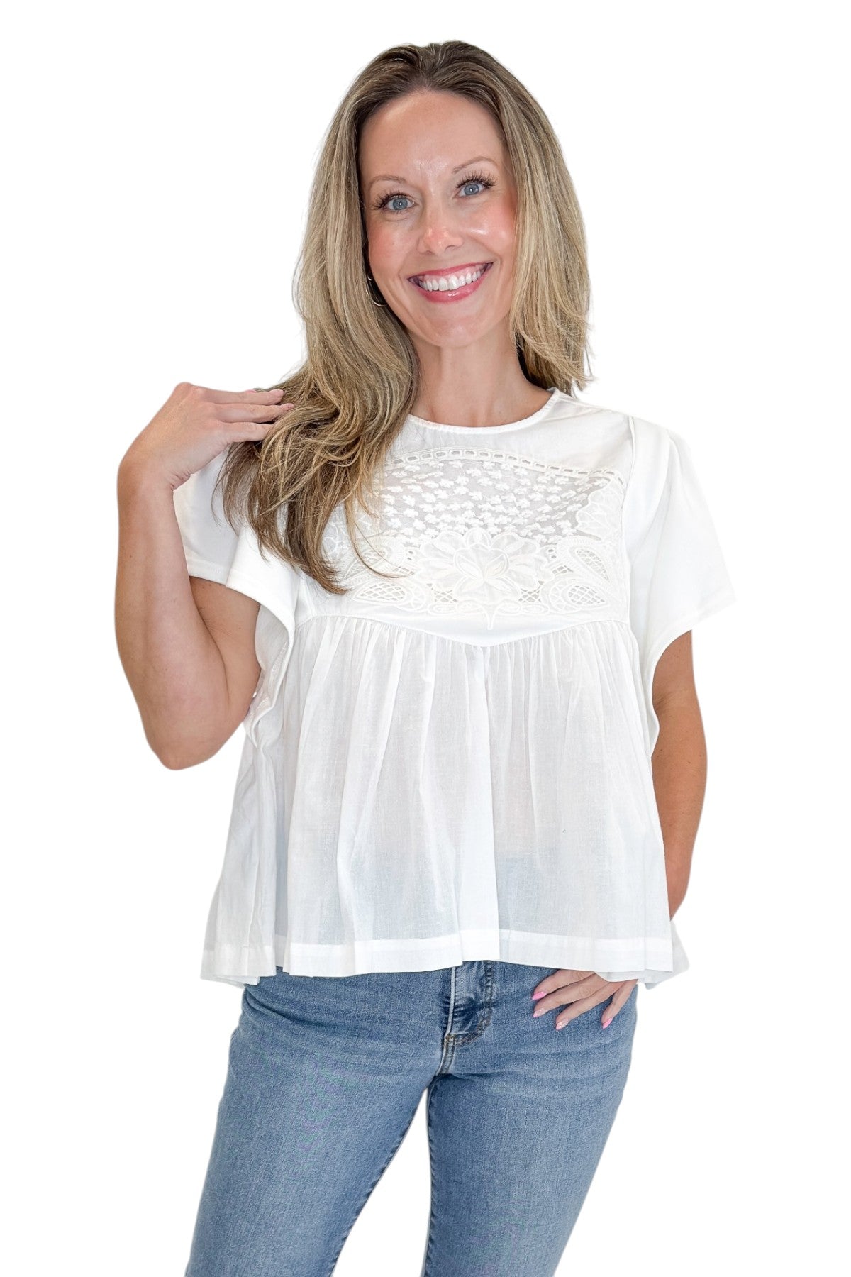 Front view of woman wearing Swagger Boutique’s White Embroidered Peplum Top with jeans against white studio background.