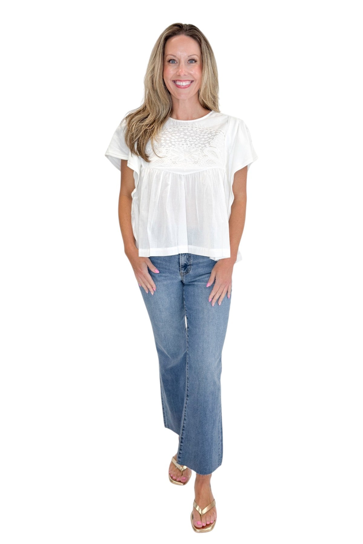 Front view of woman wearing Swagger Boutique’s White Embroidered Peplum Top with jeans against white studio background.