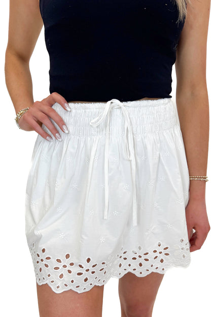 Front detail view of woman wearing Swagger Boutique’s White Eyelet Skort with black tank against white studio background.