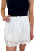 Front detail view of woman wearing Swagger Boutique’s White Eyelet Skort with black tank against white studio background.