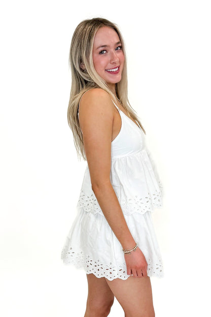 Side view of woman wearing Swagger Boutique’s White Eyelet Skort with matching tank against white studio background.