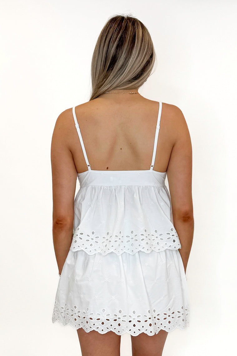 Back view of woman wearing Swagger Boutique’s White Eyelet Skort with matching tank against white studio background.