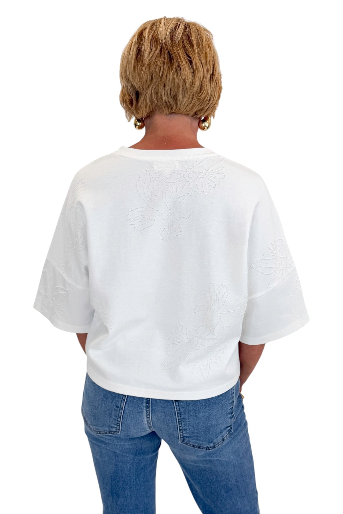 Back view of woman wearing Swagger Boutique’s White Floral Embroidered Short Sleeve Sweatshirt by Entro with jeans against white studio background.