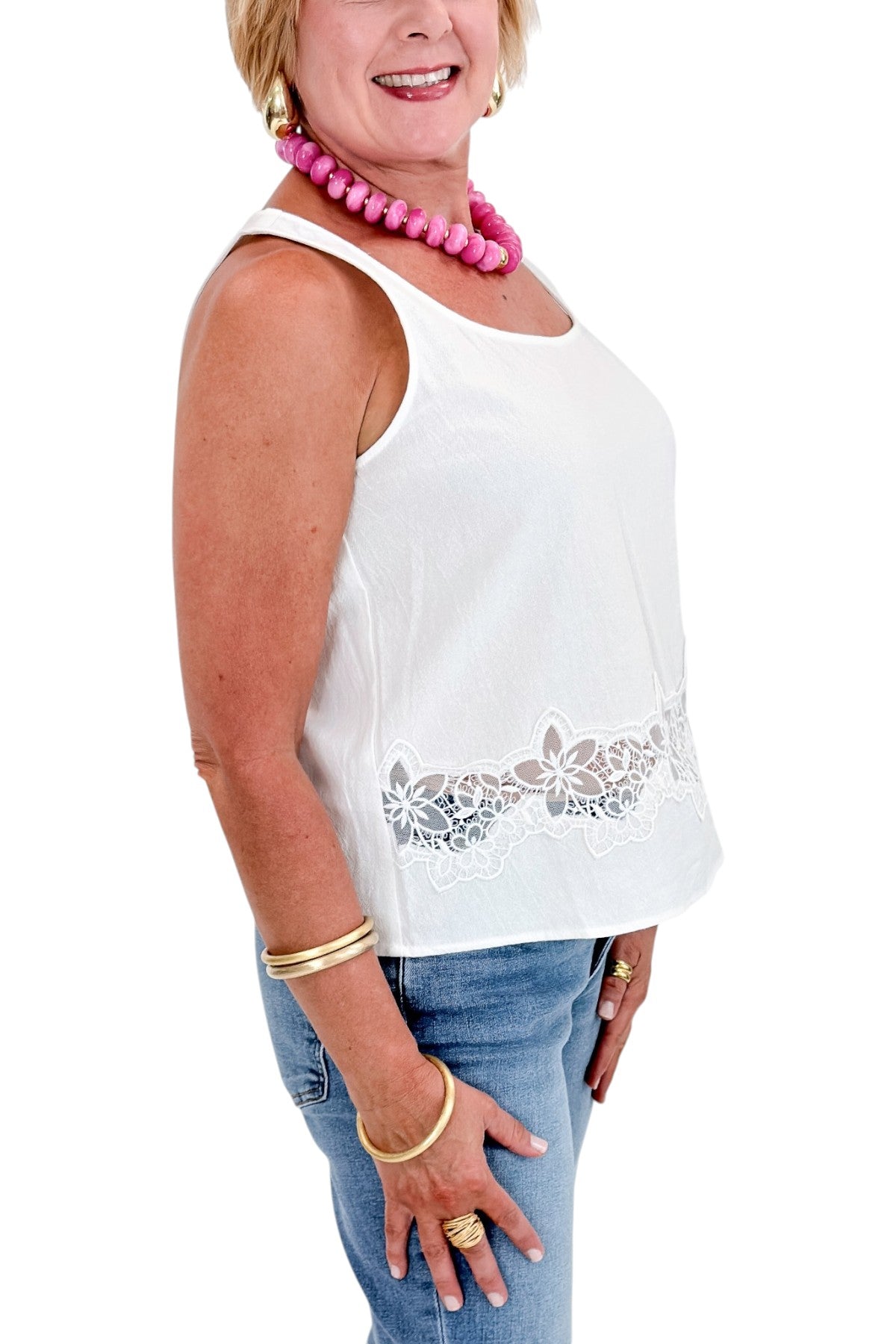 Side view of woman wearing Swagger Boutique’s White Lace Embroidered Detail Tank with jeans against white studio background.