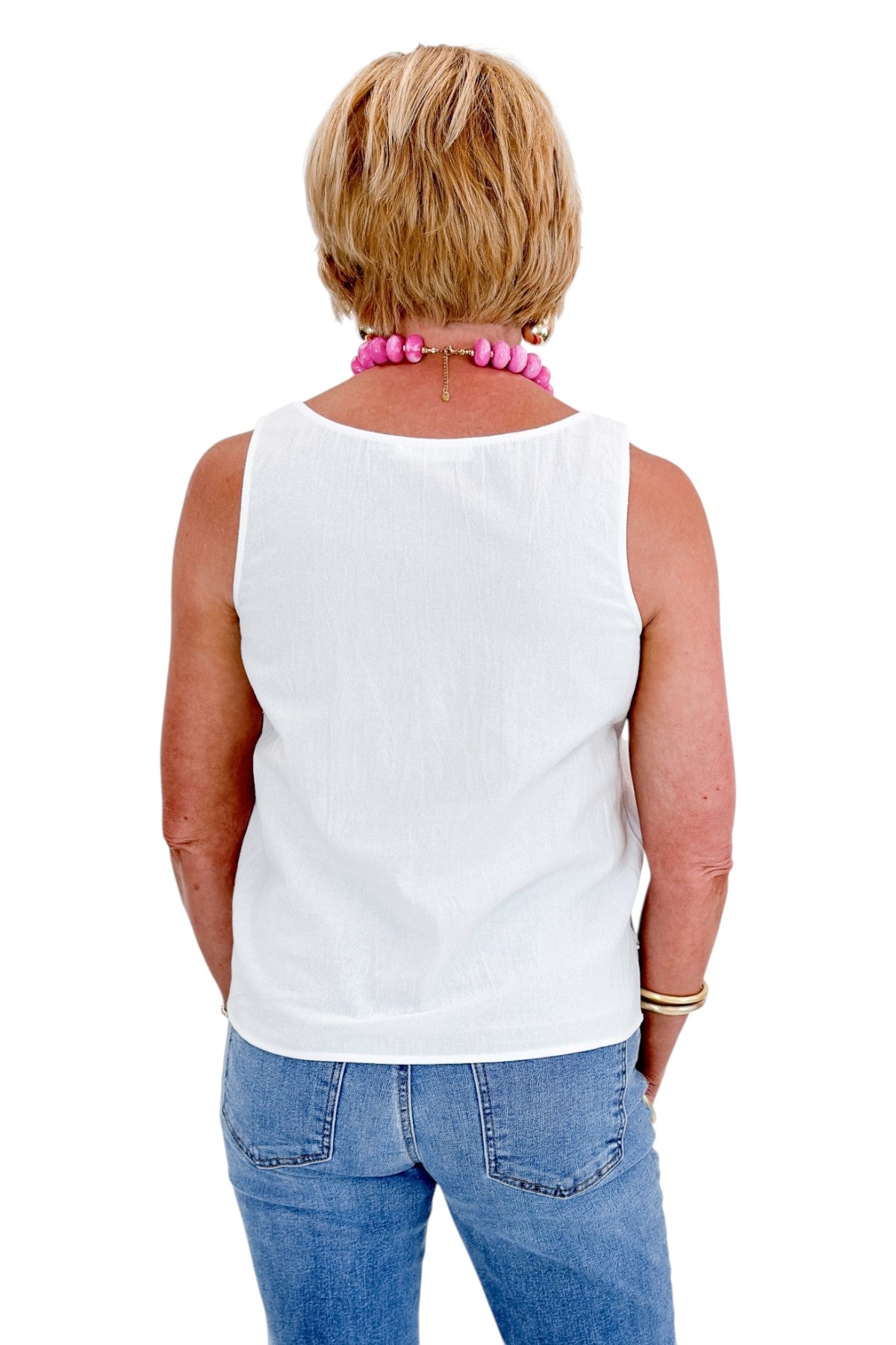 Back view of woman wearing Swagger Boutique’s White Lace Embroidered Detail Tank with jeans against white studio background.