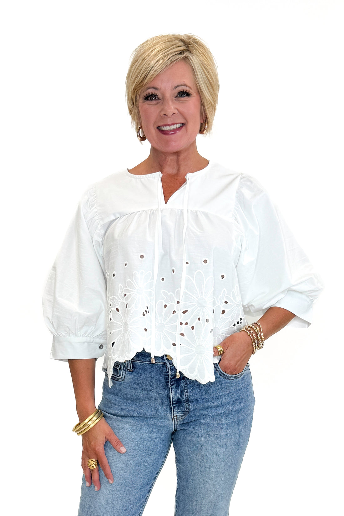 Front view of woman wearing Swagger Boutique’s White Puff Sleeve Eyelet Top with jeans against white studio background.