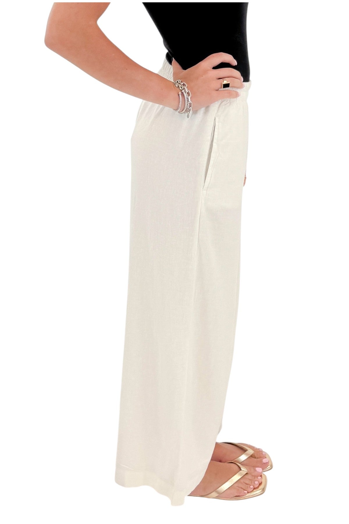 Side detail view of woman wearing Swagger Boutique’s White Scout Linen Pants by Z Supply with top against white studio background.