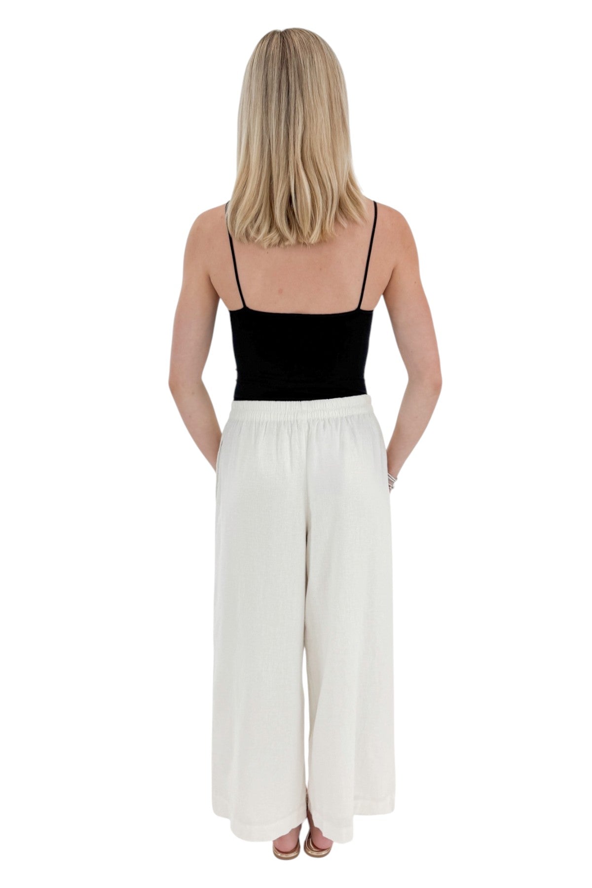 Back view of woman wearing Swagger Boutique’s White Scout Linen Pants by Z Supply with top against white studio background.
