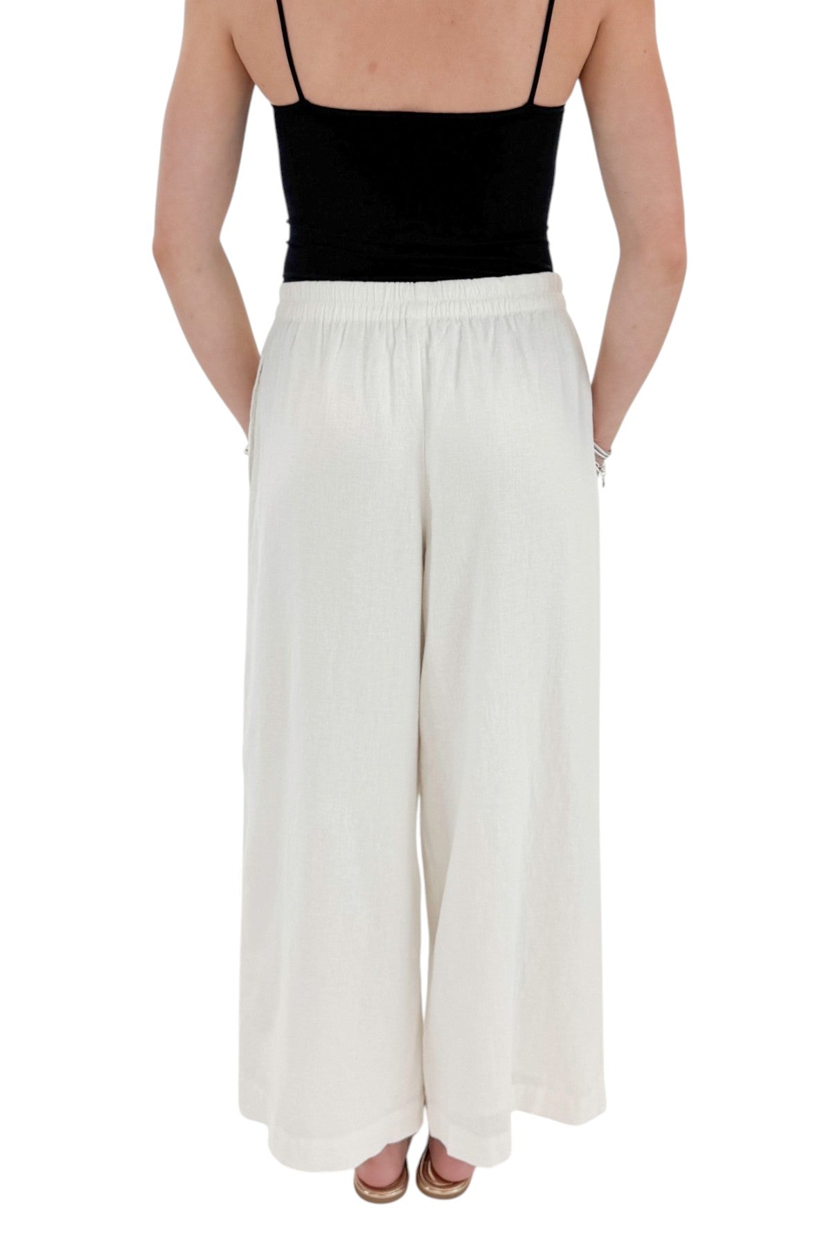 Back view of woman wearing Swagger Boutique’s White Scout Linen Pants by Z Supply with top against white studio background.