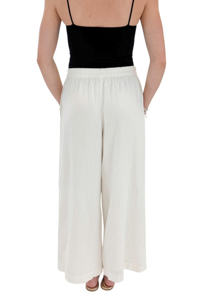 Back view of woman wearing Swagger Boutique’s White Scout Linen Pants by Z Supply with top against white studio background.