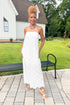 Front view of woman wearing Swagger Boutique’s White Strapless Eyelet Midi Dress by Entro with sandals standing outside by a bench.