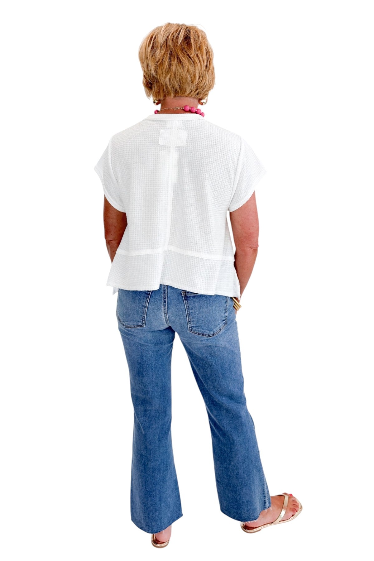 Back view of woman wearing Swagger Boutique’s White Waffle Knit Tee with jeans against white studio background.