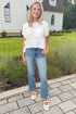 Front view of woman wearing Swagger Boutique’s White Waffle Knit Tee with jeans standing outside by a yard. 