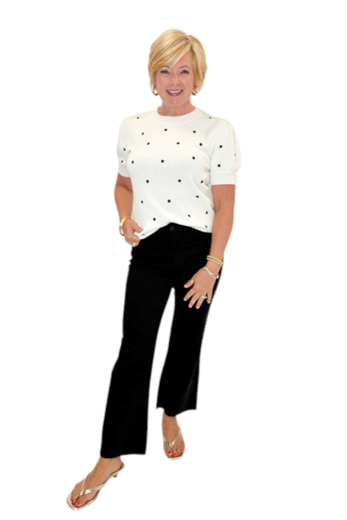 Front view of woman wearing Swagger Boutique’s White With Black Polka Dot Short Sleeve Sweater with jeans against white studio background.