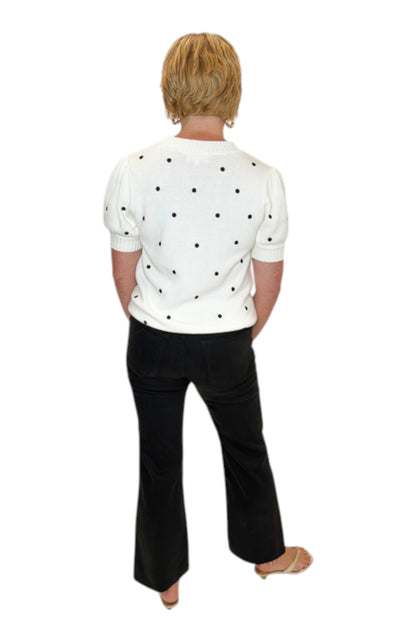 Back view of woman wearing Swagger Boutique’s White With Black Polka Dot Short Sleeve Sweater with jeans against white studio background.