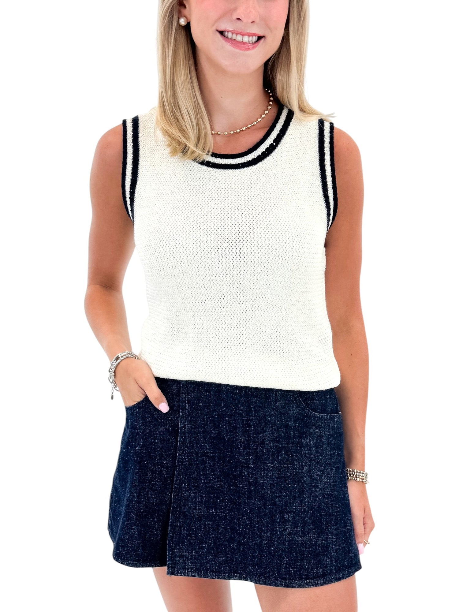 Front view of woman wearing Swagger Boutique’s White With Navy Lining Sweater Tank by Skies Are Blue with skort against white studio background.