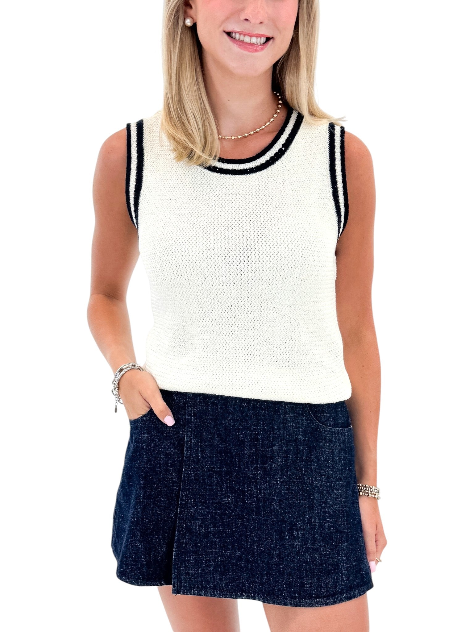 Front view of woman wearing Swagger Boutique’s White With Navy Lining Sweater Tank by Skies Are Blue with skort against white studio background.