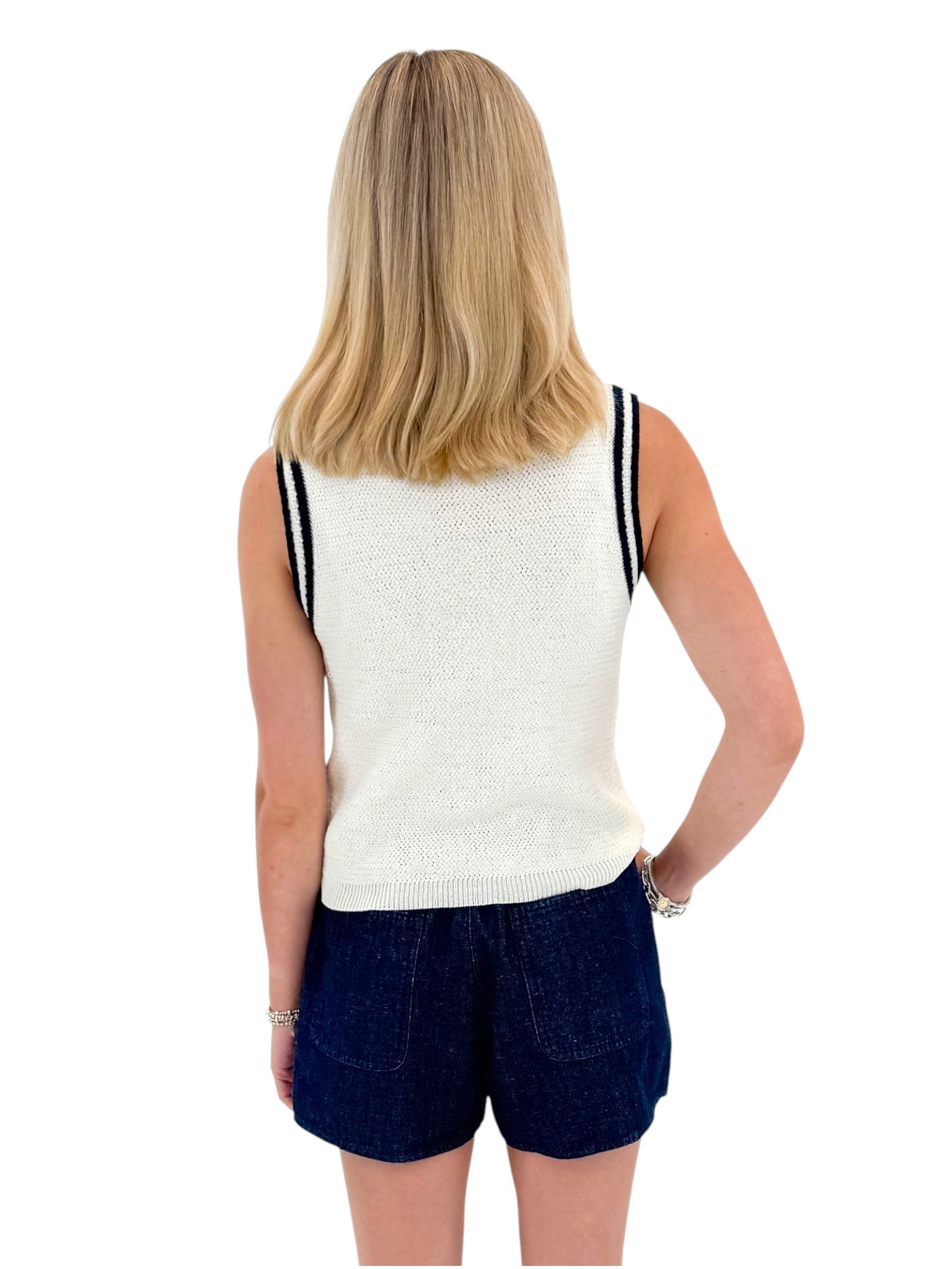 Back view of woman wearing Swagger Boutique’s White With Navy Lining Sweater Tank by Skies Are Blue with skort against white studio background.