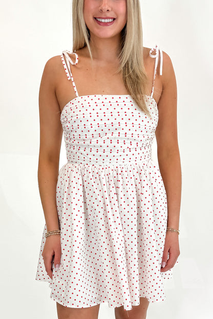 Front detail view of woman wearing Swagger Boutique’s White With Red Polka Dots Tie Strap Dress with sandals against white studio background.