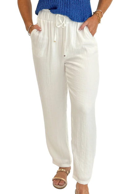 Front detail view of woman wearing Swagger Boutique’s White Woven Pants with blue tank against white studio background.
